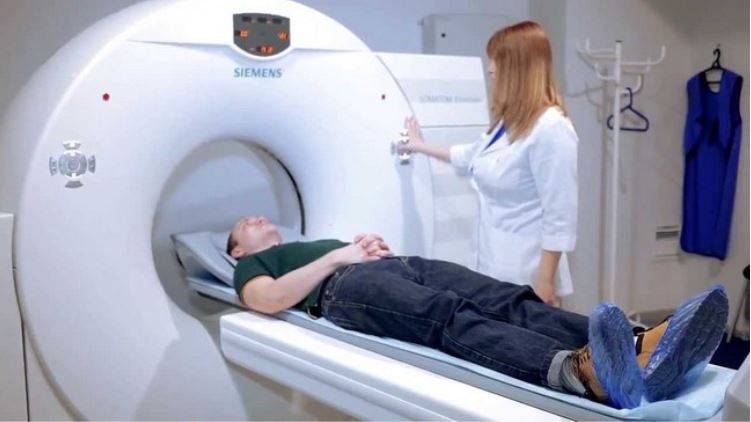 нешний вид компьютерного томографа и положение пациента на столе аппарата перед началом исследования